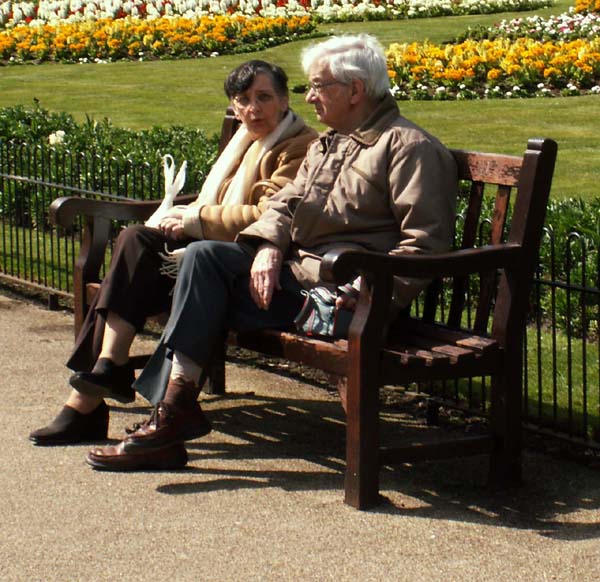 An elderly couple on a bench in Leamington Spa park.
